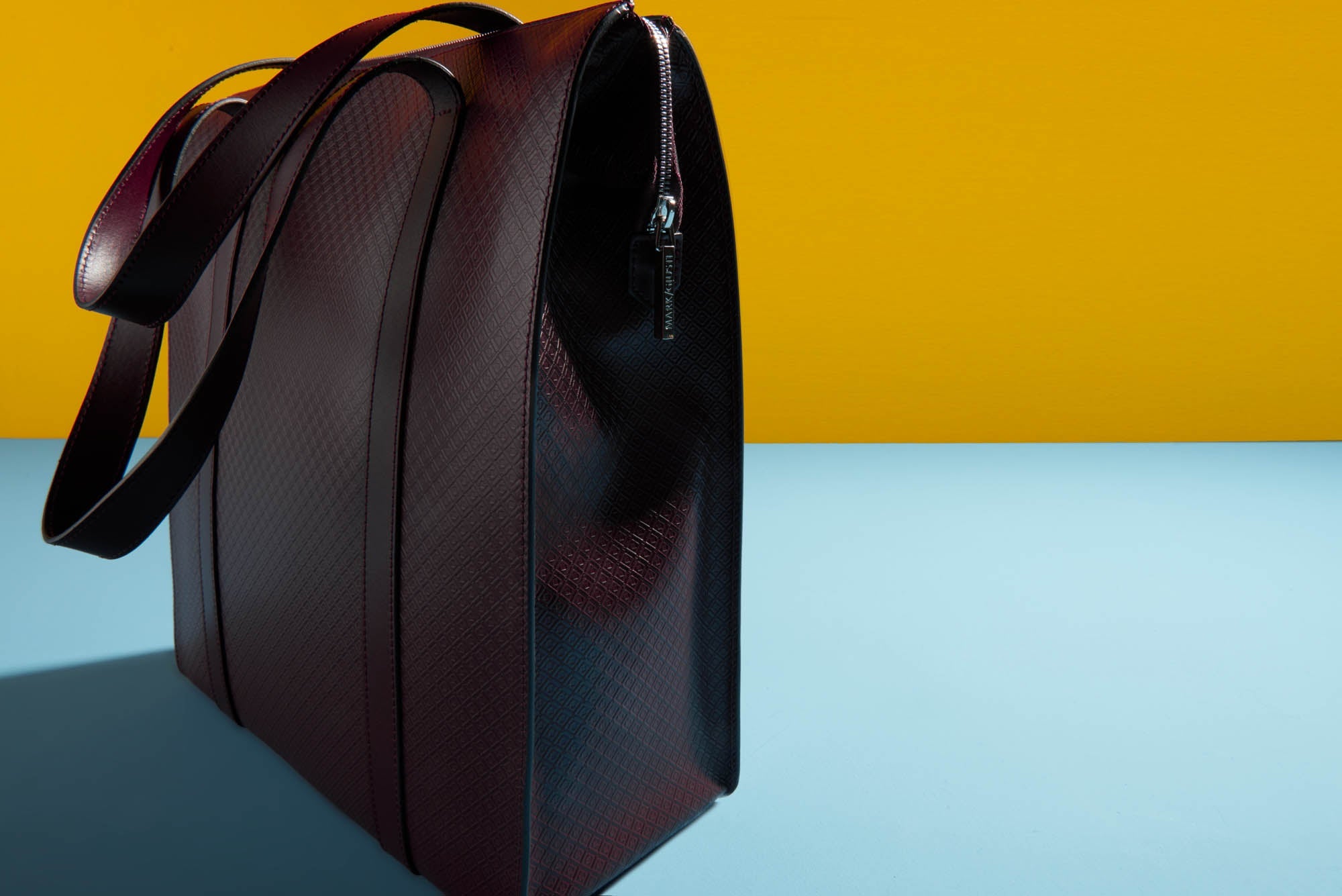 The MARK / GIUSTI Shoreditch tote leather bag photographed artistically on a minimalist colourful background, highlighting both the sharpness of the details and the softness of the leather.