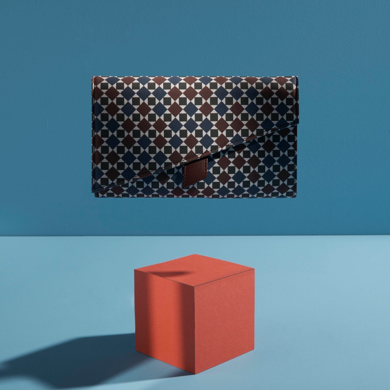 Artistic campaign photo shoot featuring the iconic Soho leather clutch in the London Calling signature mosaic pattern, displayed in a modern, stylish composition.
