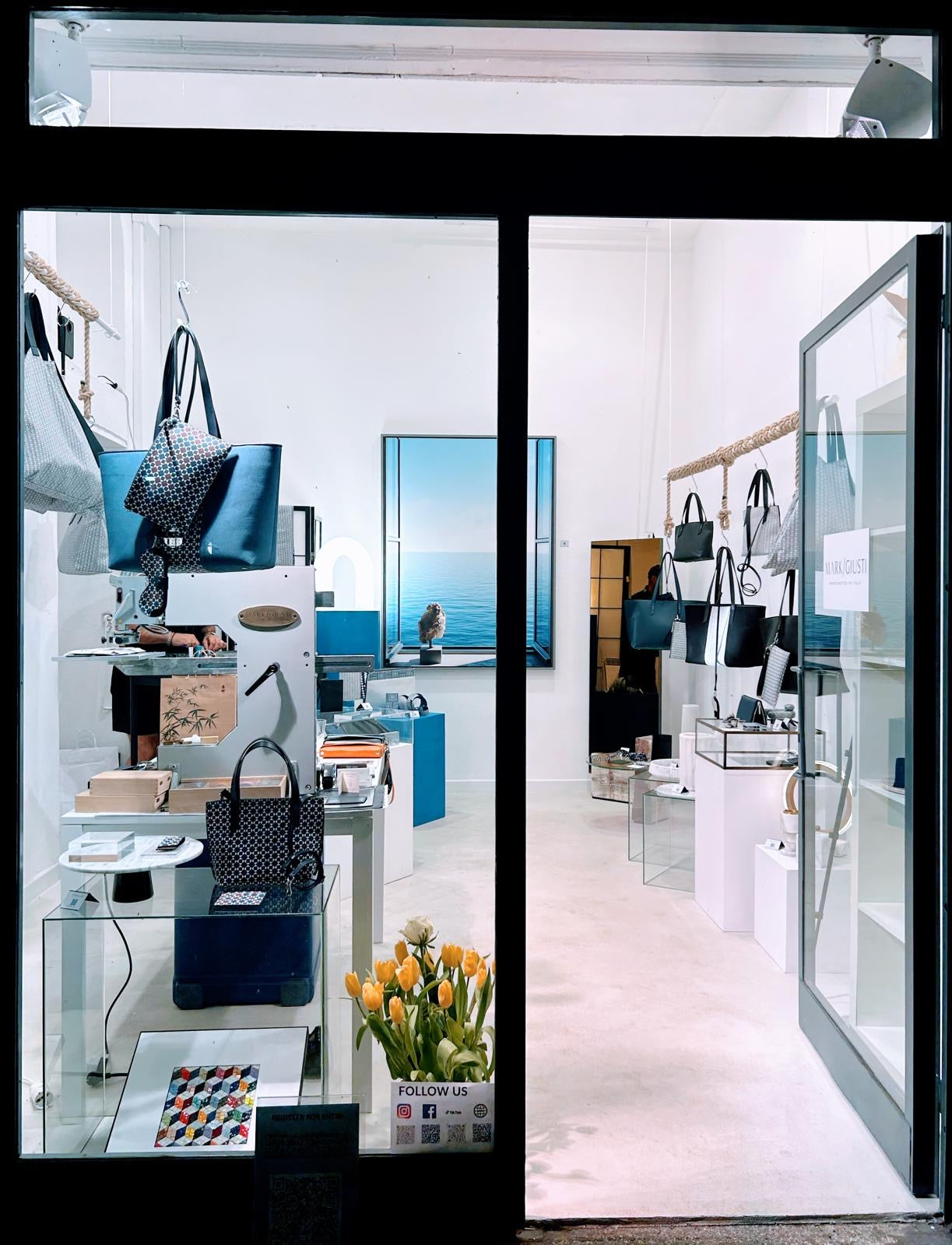 The World of MARK / GIUSTI's "This is Not a Store: Experiential Pop-Up" during Milan Fashion Week 2024, showcasing an artistic display of luxury bags and accessories. The space, located in Milan, invites visitors into a creative lab, blending elements of art, architecture, and design with fashion and well-being, offering a multi-sensory journey into the brand’s world.