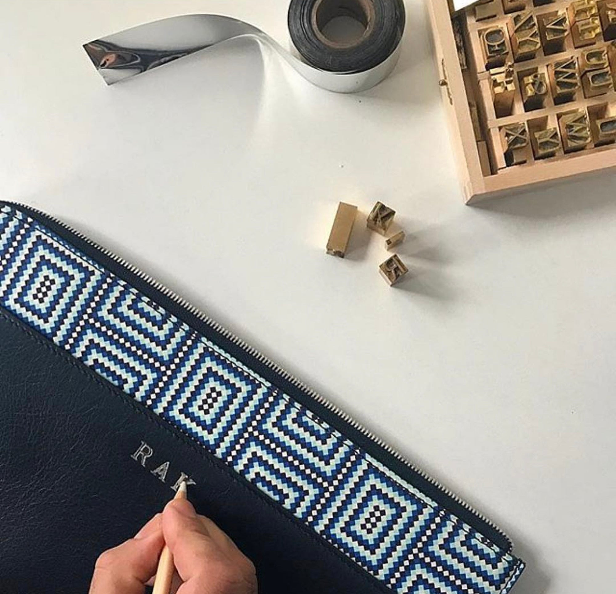 Close-up of bespoke personalisation process for MARK / GIUSTI’s luxury leather accessory, featuring hand-stamped initials and signature mosaic pattern.