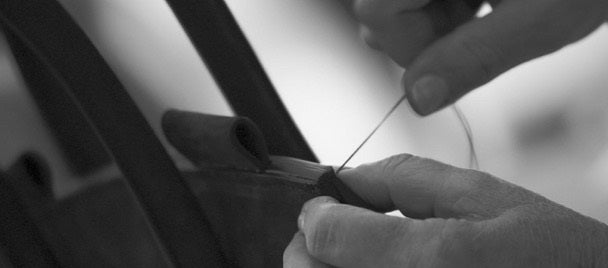 Hand-stitching process showcasing the craftsmanship heritage at MARK/GIUSTI, highlighting the brand's commitment to preserving traditional artisan skills and sustainable luxury.