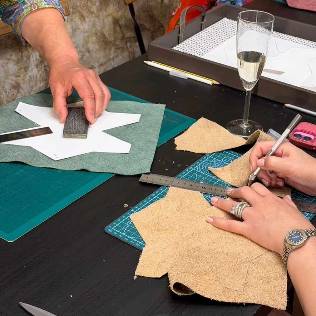 Two people at MARK / GIUSTI Leather Goods Store and atelier cutting the leather for their handcrafted wallet during the leather craft workshop
